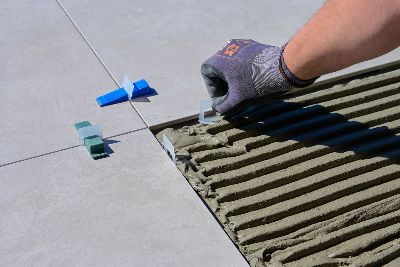 Installer spreading thinset with a notched trowel and setting tile with leveling spacers